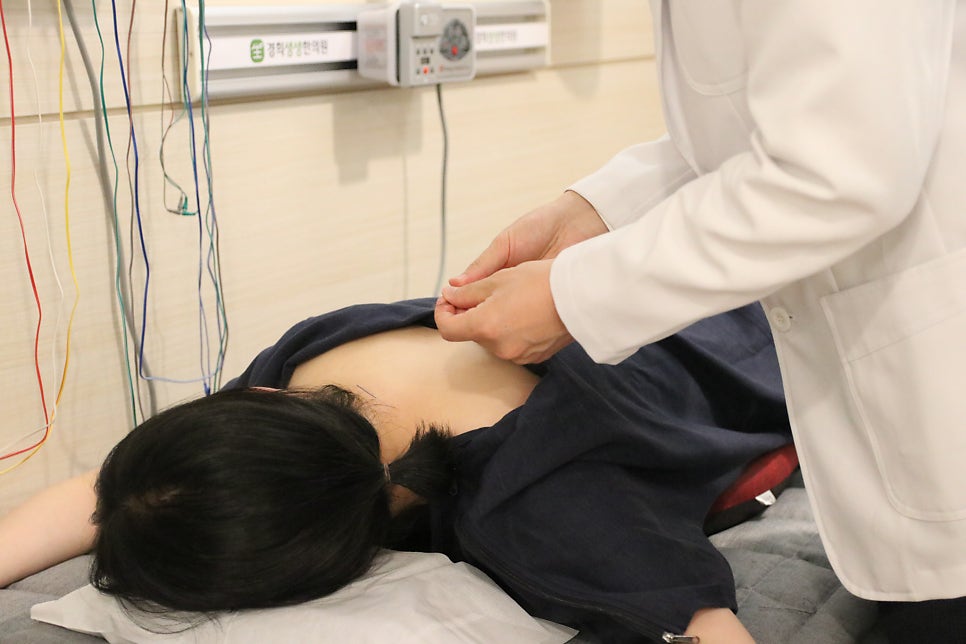 엎드린 환자의 목과 어깨를 풀어 주는 거북목 치료 모습
