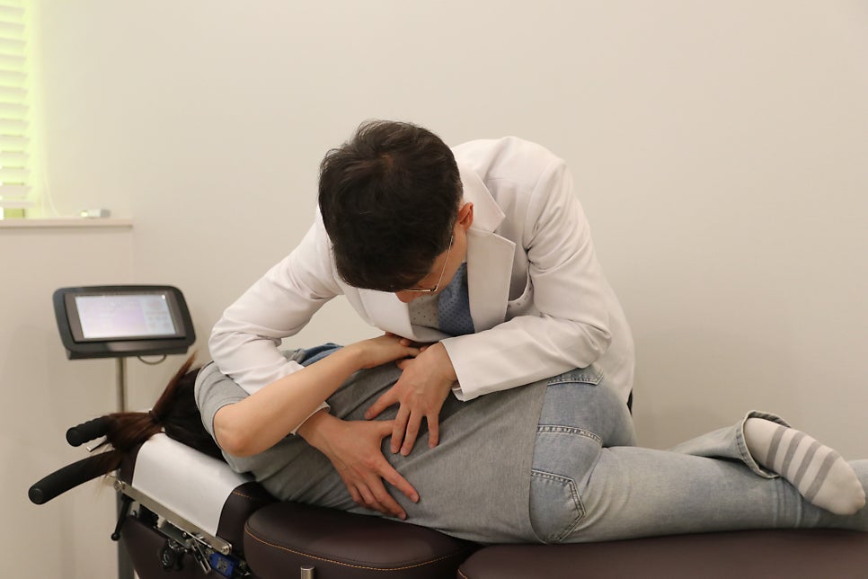 옆으로 누운 환자의 허리와 골반을 추나로 교정하는 모습